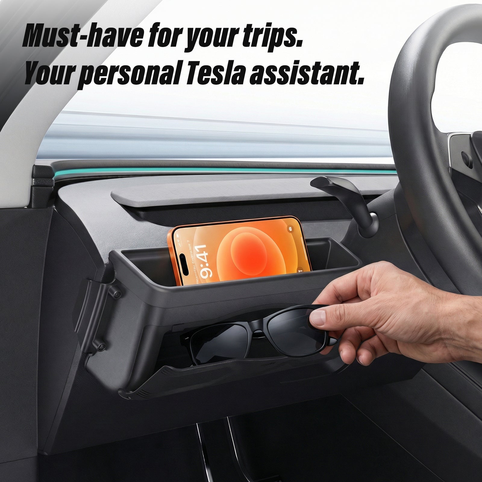 Driver-side dashboard organizer for Tesla, featuring a phone holder and sunglasses compartment. A hand is placing sunglasses into the sleek black storage box mounted on the instrument panel.